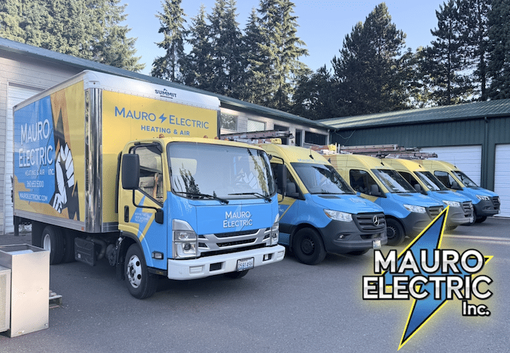 Row of Mauro Electric service trucks in blue and yellow parked outside a workshop