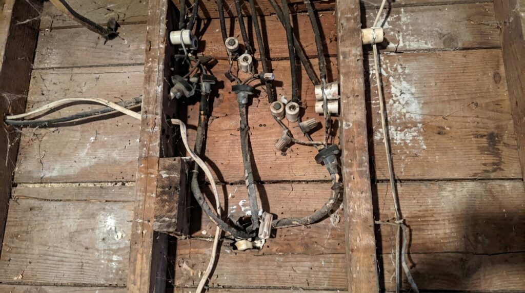 Close-up of real knob-and-tube wiring with wire nuts on wood floor joists